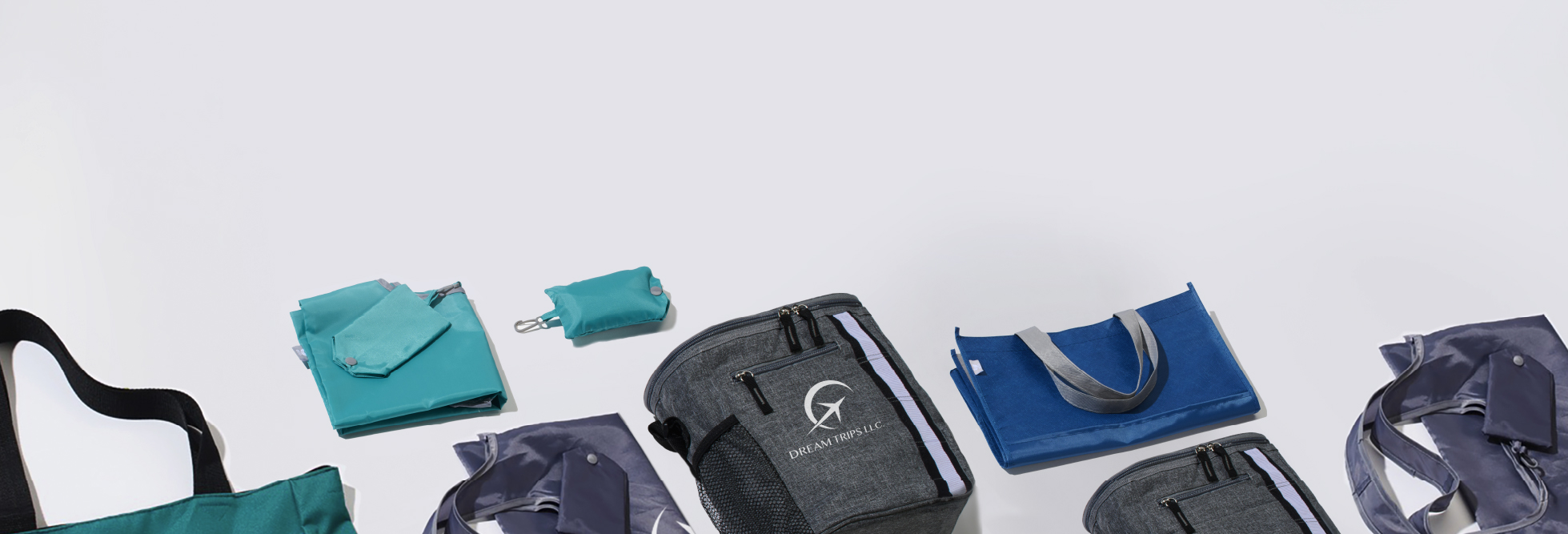 A variety of  branded bags and promotional bags layed out on display from blue messenger bags, backpacks, and tote bags with straps.